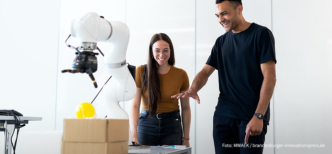 Zwei Personen, die mit einem Roboterarm interagieren