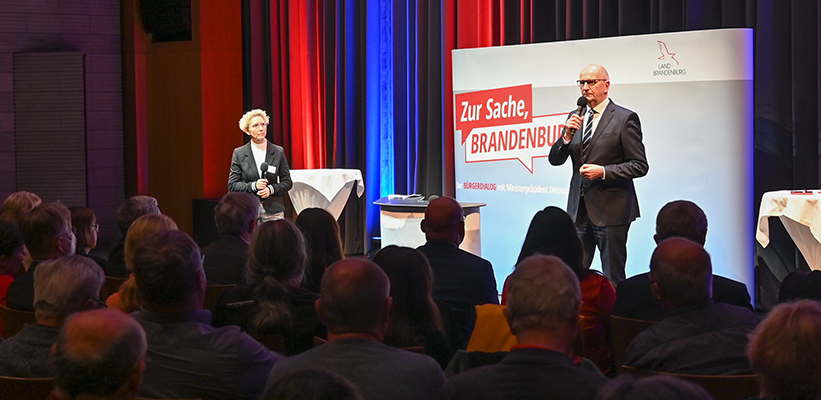 Ministerpräsident Dr. Dietmar Woidke spricht auf einem Bürgerdialog zu den Gästen im Veranstaltungssaal