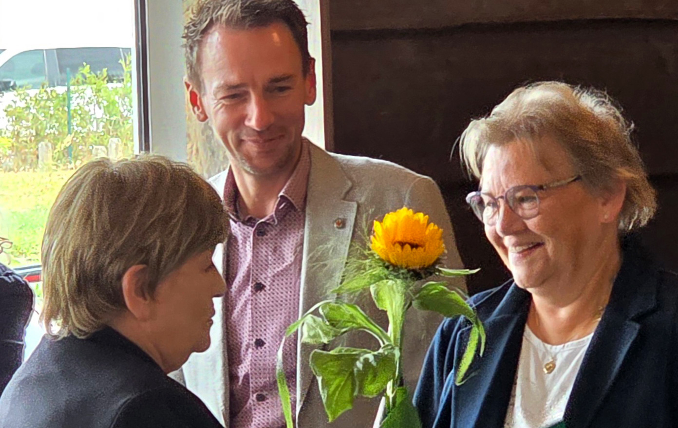 Foto: 3 Personen und ein Sonnenblume wird überreicht Foto: 3 Personen und ein Sonnenblume wird überreicht