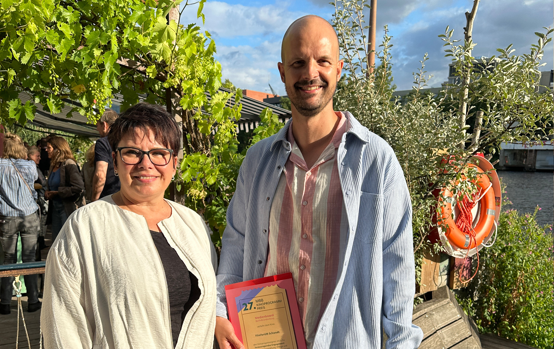 Foto: eine Frau und ein Mann mit der Urkunde in der Hand schauen in die Kamera Foto: eine Frau und ein Mann mit der Urkunde in der Hand schauen in die Kamera
