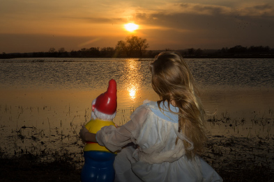 Foto: Mädchen mit Gartenzwerg vor einem Sonneaufgang Foto: Mädchen mit Gartenzwerg vor einem Sonneaufgang