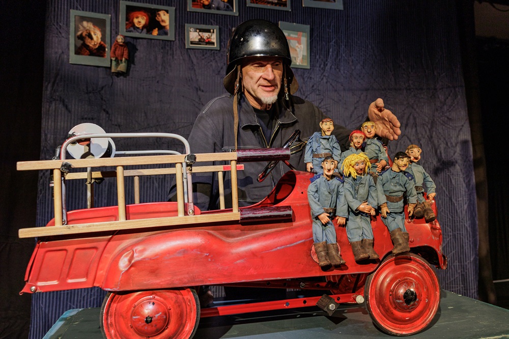 Foto: Puppenspieler präsentiert eine Feuerwehr mit 7 Puppen darauf Foto: Puppenspieler präsentiert eine Feuerwehr mit 7 Puppen darauf