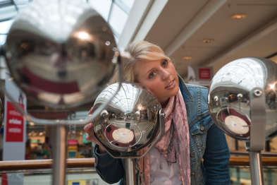 Foto: Frau lauscht an Metallkugel Foto: Frau lauscht an Metallkugel