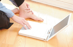 Foto: Frauenhand am Laptop, der auf dem Fußboden liegt Foto: Frauenhand am Laptop, der auf dem Fußboden liegt