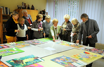 Foto: Jurymitglieder stehen um einen Tisch mit Zeichnungen herum. Foto: Jurymitglieder stehen um einen Tisch mit Zeichnungen herum.