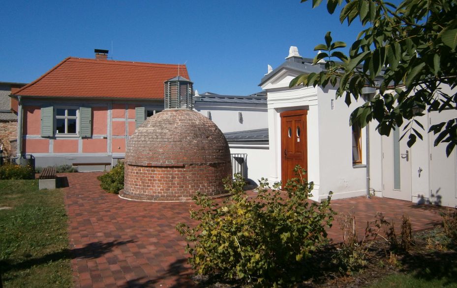 Vor einem Fachwerkhaus befindet sich ein Kuppelbau.