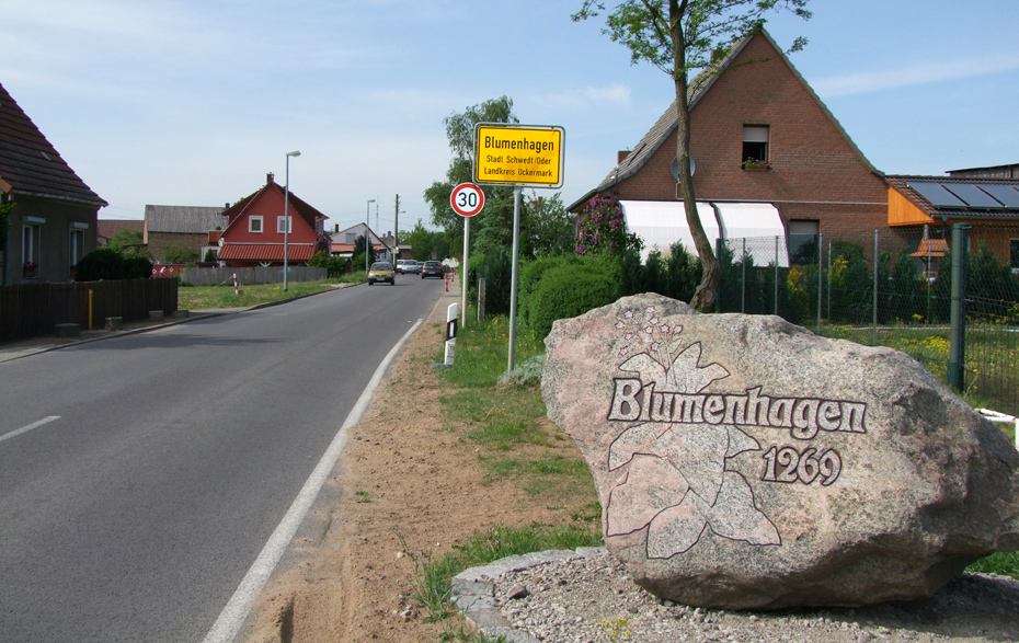 Foto: Straße mit Ortseingangsschild und Findling mit Ortsnamen