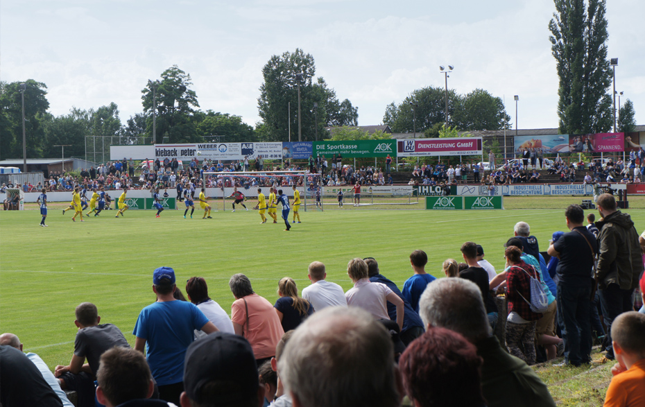 Foto: Fußballspiel auf dem Sportplatz mit Publikum