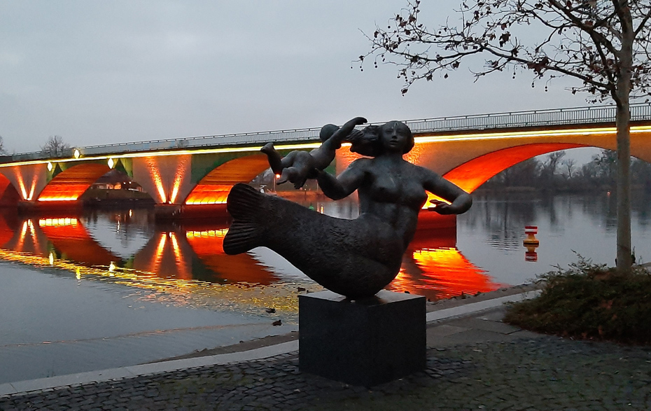 Foto: Plastik Seejungfrau vor der beleuchteten Brücke Foto: Plastik Seejungfrau vor der beleuchteten Brücke