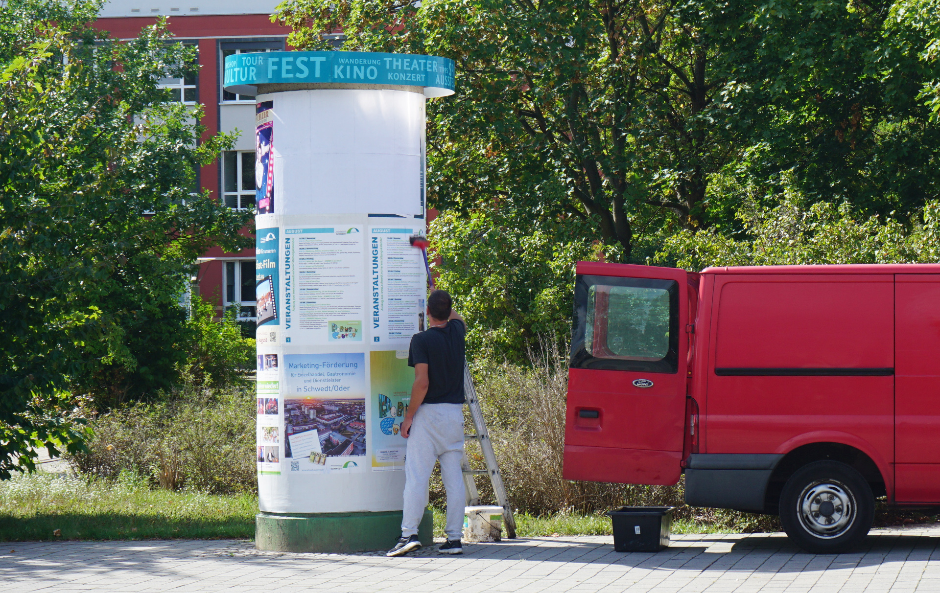 Foto: Dienstleister klebt Plakate an die Litfaßsäule Foto: Dienstleister klebt Plakate an die Litfaßsäule