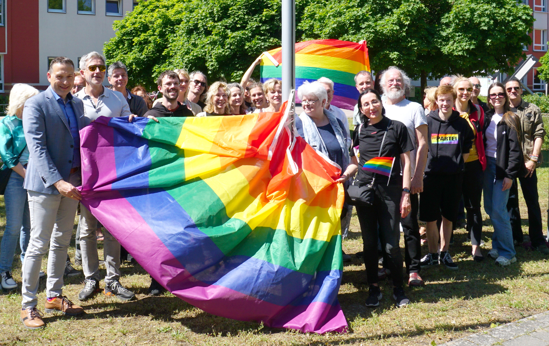 Foto: Gruppenfoto mit Regenbogenfahne Foto: Gruppenfoto mit Regenbogenfahne
