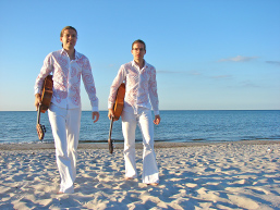 Foto: Zwei Musiker spazieren mit ihren Gitarren am Strand. Foto: Zwei Musiker spazieren mit ihren Gitarren am Strand.