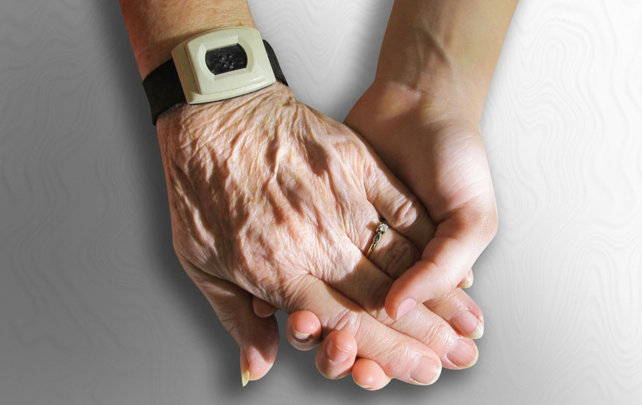 Foto: junge Hand hält ältere Hand mit Notrufknopf Foto: junge Hand hält ältere Hand mit Notrufknopf
