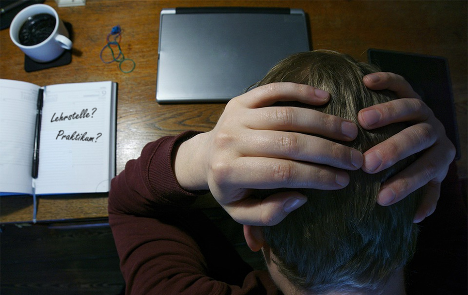 Foto: Blick von oben auf eine Tisch mit Laptop, Tasse und Kalender, darüber Hände am Kopf haltender Jugendliche Foto: Blick von oben auf eine Tisch mit Laptop, Tasse und Kalender, darüber Hände am Kopf haltender Jugendliche