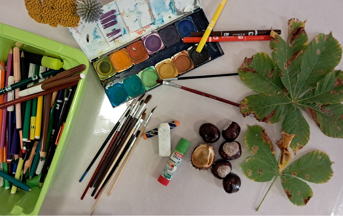 Foto: auf dem Tisch liegen Stift, Pinsel, Tuschkasten, Kleber, Kastaniern und Blätter Foto: auf dem Tisch liegen Stift, Pinsel, Tuschkasten, Kleber, Kastaniern und Blätter