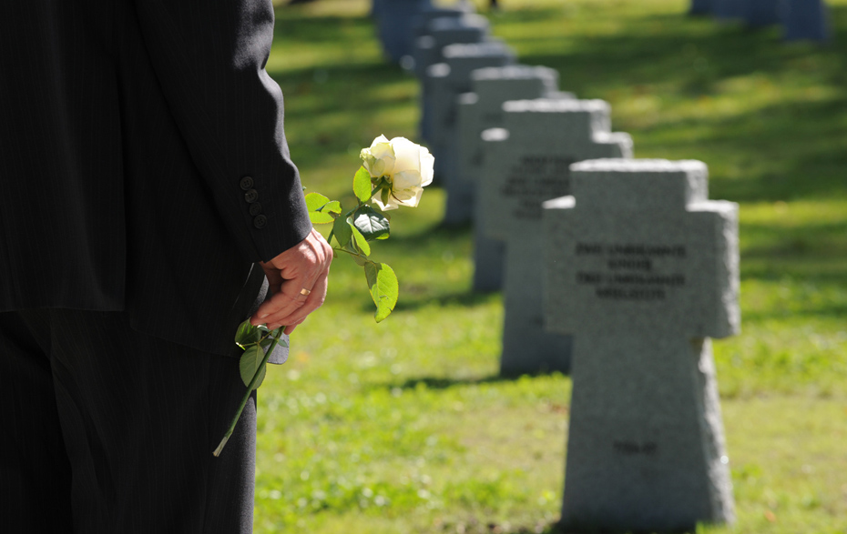 Foto: weiße Rose in der Hand auf einem Kriegsgräberfriedhof Foto: weiße Rose in der Hand auf einem Kriegsgräberfriedhof