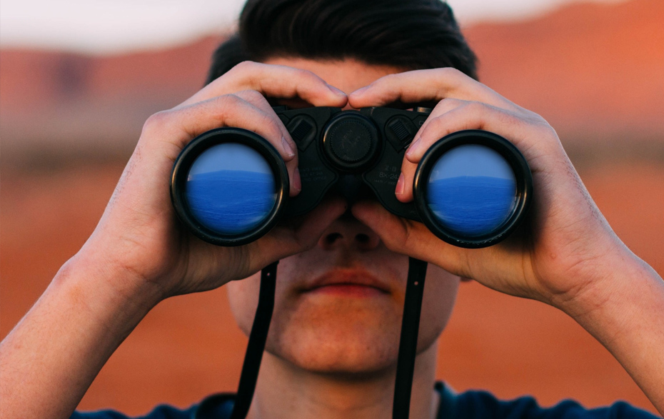 Foto: junger Mann schaut durch ein Fernglas Foto: junger Mann schaut durch ein Fernglas