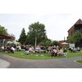 Mehrere Kinder sitzen auf den Bänken im Museumsgarten und schauen zu