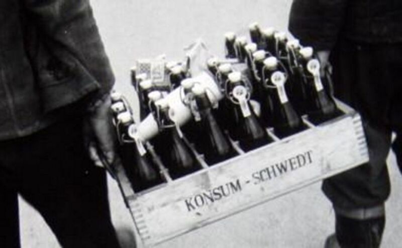 zwei Männer, die einen Kasten mit Bierflaschen tragen zwei Männer, die einen Kasten mit Bierflaschen tragen