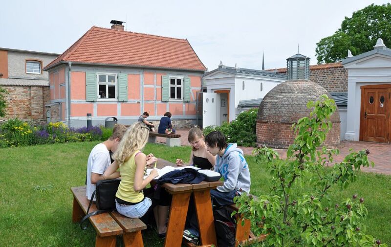 Foto: Schüler*innen sitzen an einem Tisch und lesen. Im Hintergrund ist das Jüdische Museum Schwedt zu sehen. Foto: Schüler*innen sitzen an einem Tisch und lesen. Im Hintergrund ist das Jüdische Museum Schwedt zu sehen.