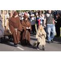 Foto: kleine Hexe läuft vor Mönchen, die einen Wagen ziehen