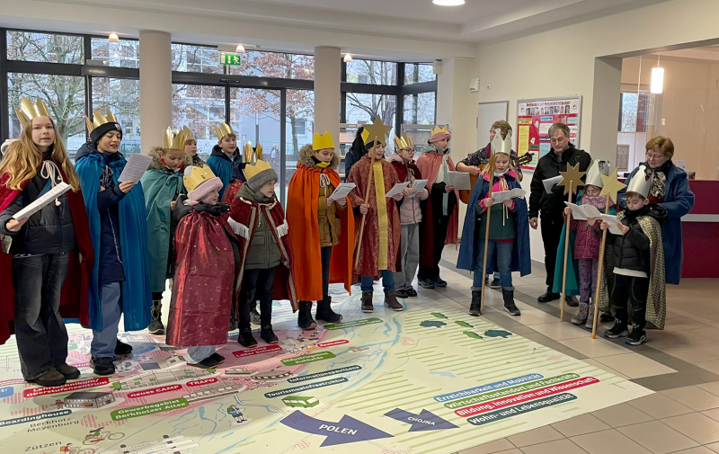 Foto: Gruppe singender Kinder mit goldenen Kronen im Rathausfoyer Foto: Gruppe singender Kinder mit goldenen Kronen im Rathausfoyer