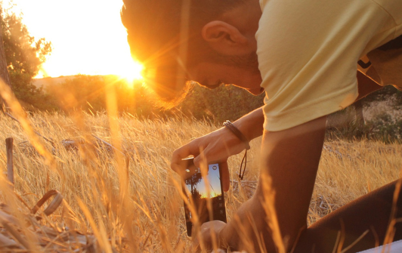 Foto: Junge beim Fotografieren der Sonne aus einer tiefen Position Foto: Junge beim Fotografieren der Sonne aus einer tiefen Position