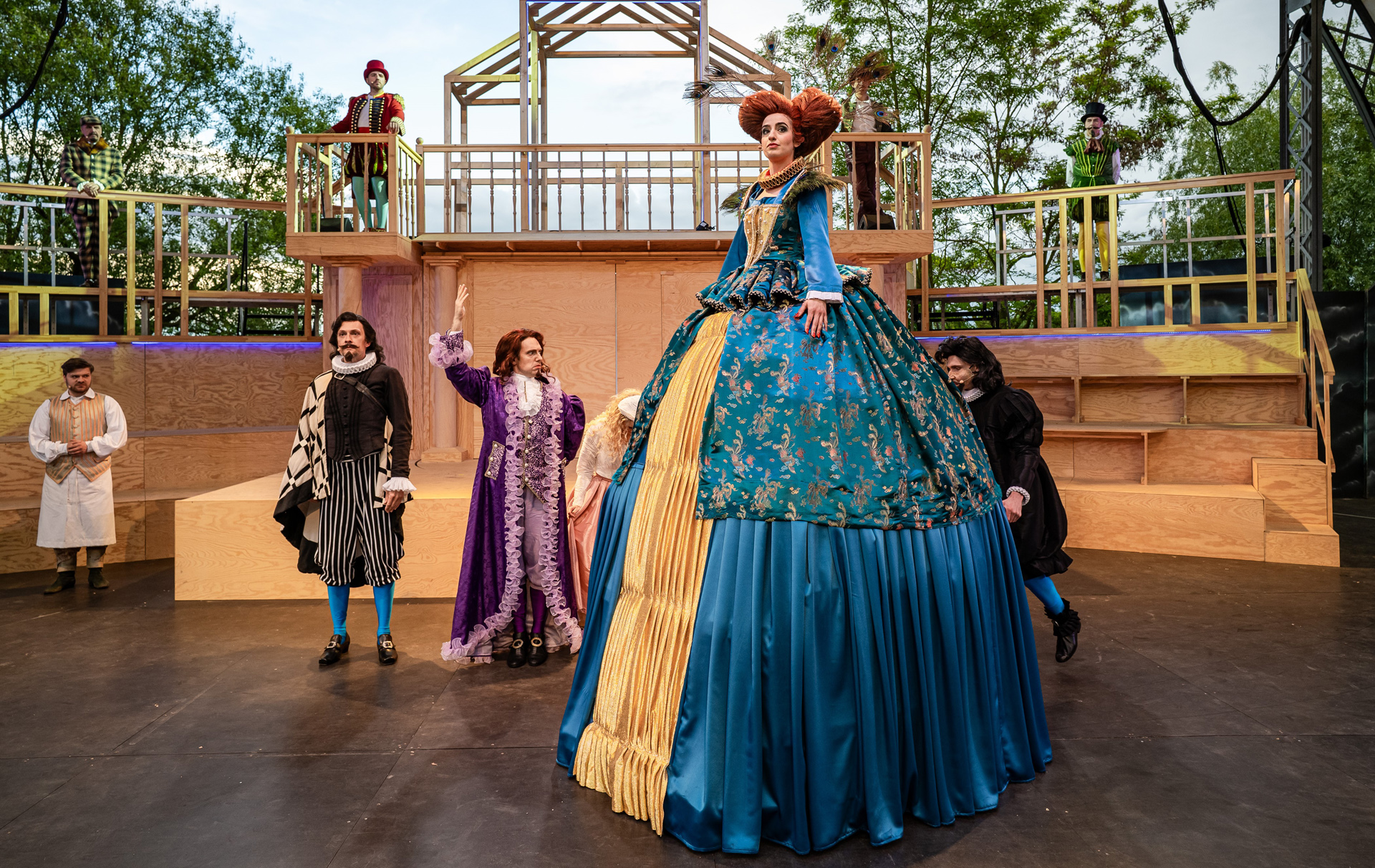 Foto: Schauspielerin in einem üppigen riesigen Kostüm umgeben von weiteren Schauspielen in Kostüm auf der Open-Air-Bühne Foto: Schauspielerin in einem üppigen riesigen Kostüm umgeben von weiteren Schauspielen in Kostüm auf der Open-Air-Bühne
